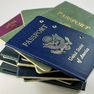 A stack of various passports, with a blue United States passport prominently on top, displaying the seal and text "United States of America."