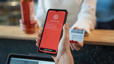Person holding a phone displaying "Verification Failed" screen, while another holds a bottle and ID card at a counter.
